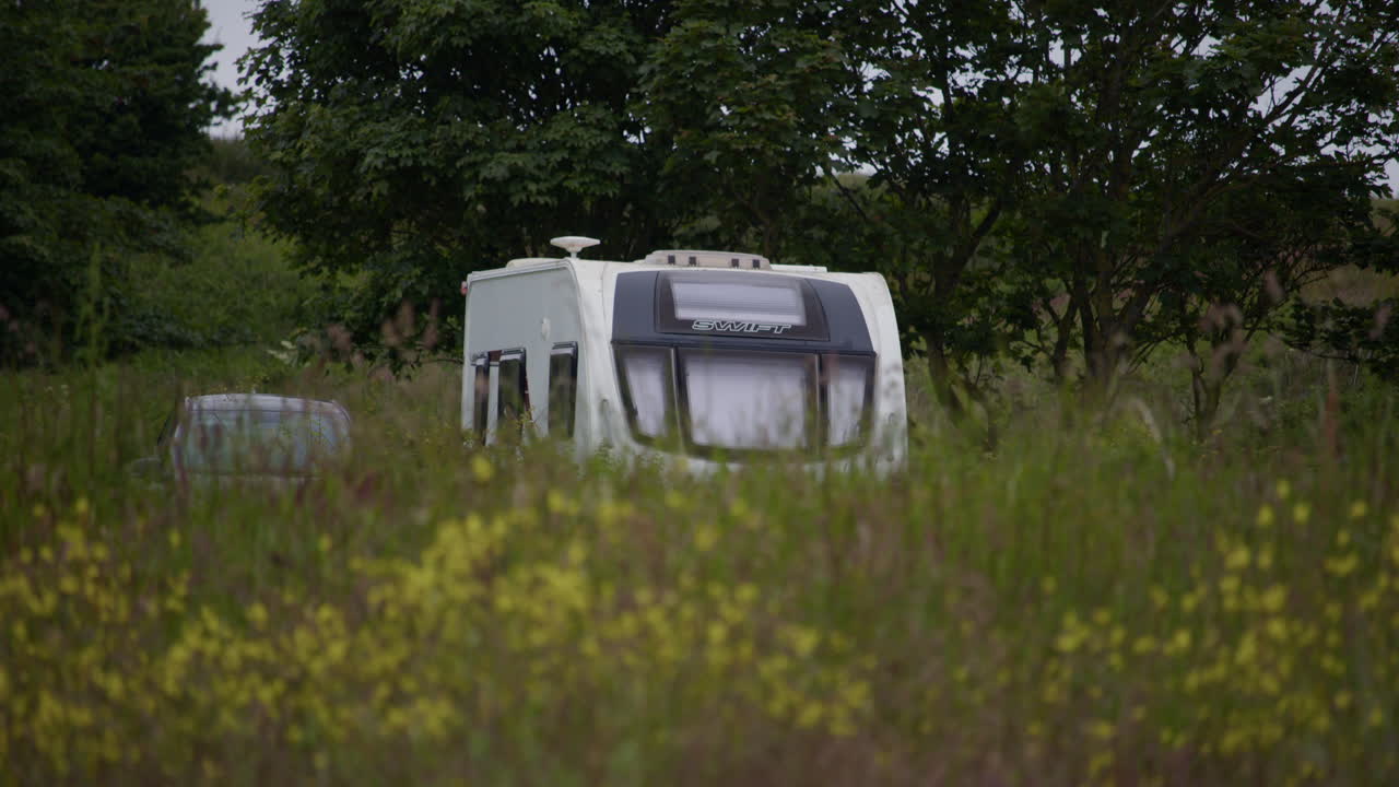 looking over a grass mound with the top of a caravan visible.