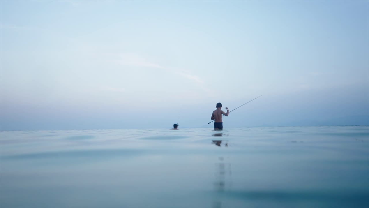 Dua Pria Memancing di Laut Tenang Saat Senja