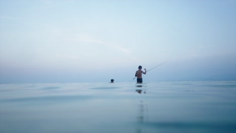 two men fishing in the calm sea at twilight