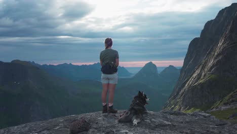 mujer excursionista con su mascota malamute de alaska en el pico grytetippen en noruega