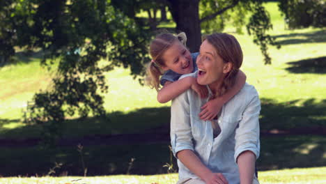 Young-mother-and-daughter-relaxing-in-the-park-together