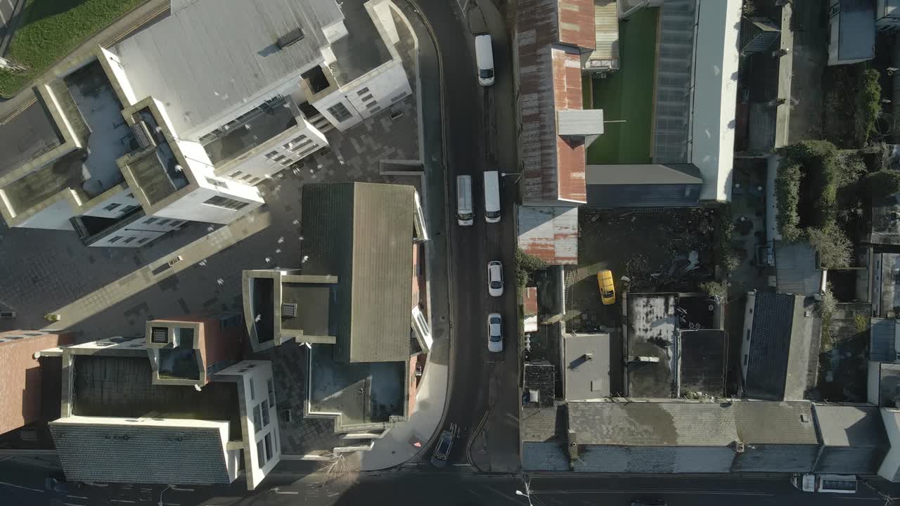Pombos voando sobre as ruas estreitas e ensolaradas de Dundalk, Irlanda, vista aérea.