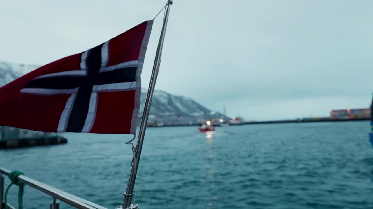 Viftende norsk nasjonalflagg, seilende fjordfartøy, patriotisk identitet