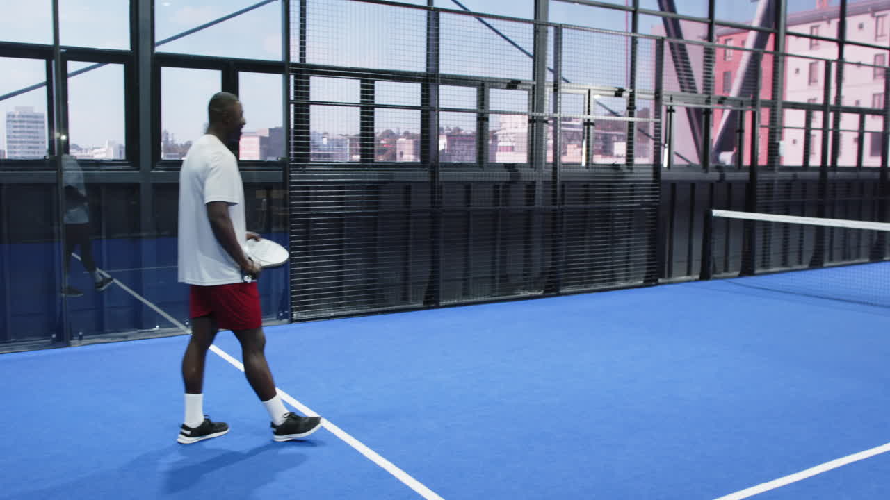 Man playing padel tennis on indoor court, preparing to hit ball