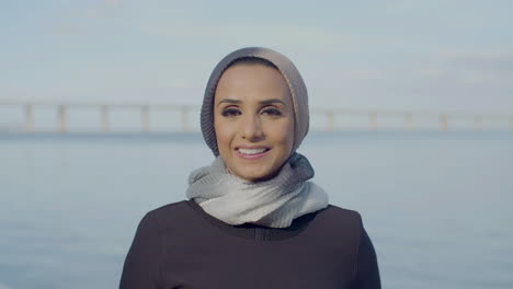 smiling arabic woman standing near the river