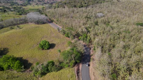 Drone-aerial-point-of-view-of-suv-car-driving-on-a-countryside-road,-revealing-large-rural-areas,-farming-landscapes-and-a-green-environment,-Costa-Rica