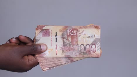 close up shot of hands revealing kenyan shilling currency money cash from the left