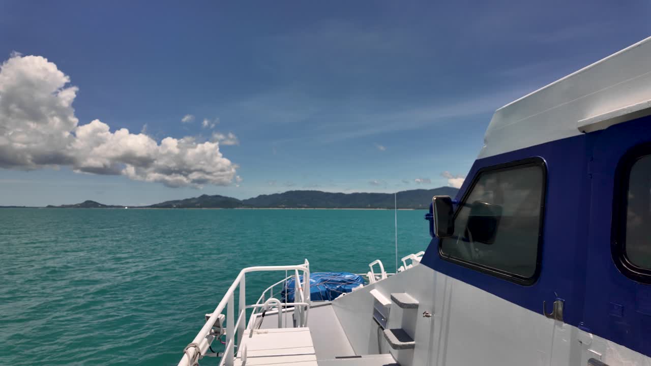 Vew from a boat deck reveals sparkling turquoise waters and a distant mountain range under a clear blue sky, capturing a perfect moment of tranquility at sea.