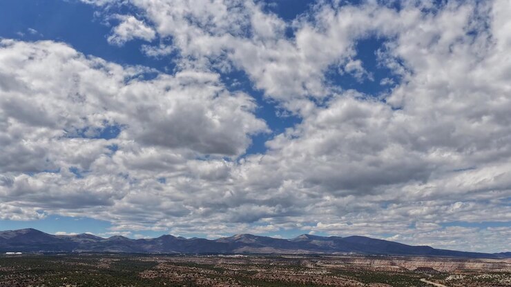 Timelapse 4K con dron captura nubes dramáticas y serenas moviéndose a través de un extenso horizonte suroeste. El paisaje celeste cinematográfico revela el movimiento atmosférico a gran altitud y la luz natural cambiante.