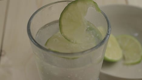 dejando caer rodajas de lima en un refrescante vaso de agua con gas