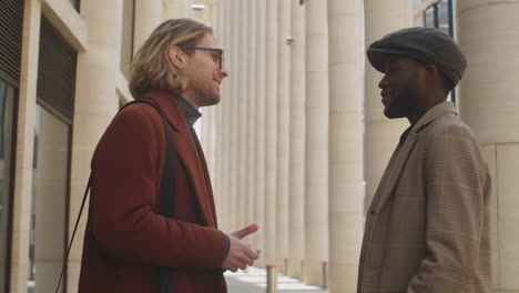 two multiethnic businessmen having talk on street in downtown