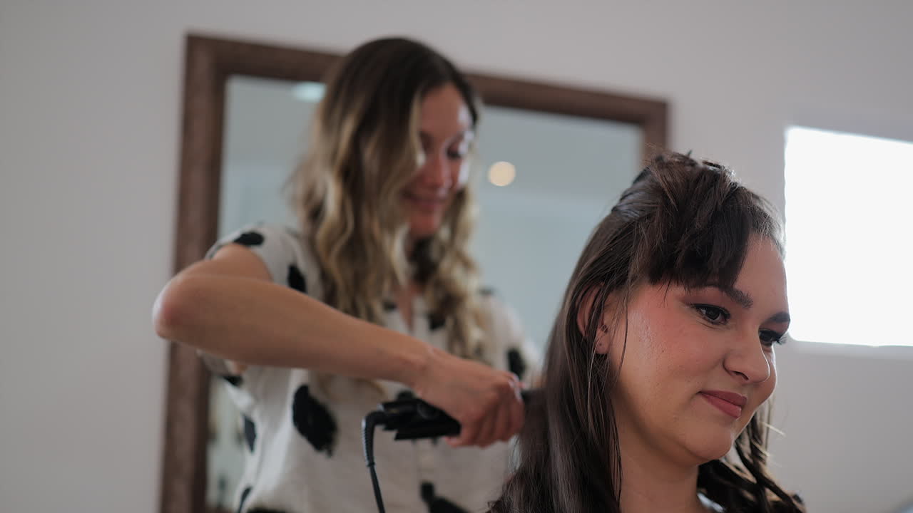 Estilista trabaja en el cabello de una joven morena antes de su boda