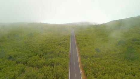 Toma-Aérea-De-Pájaros-De-Automóviles-En-Una-Carretera-Asfaltada-En-El-Paisaje-Verde-De-Madeira-Durante-El-Día-Brumoso-En-La-Isla