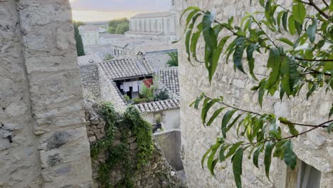 view of a small, beautiful stone house in france between house roofs and a bit of low sun over the french village