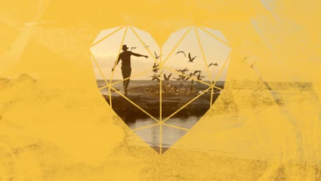 man waving arms on beach through yellow heart shaped foreground