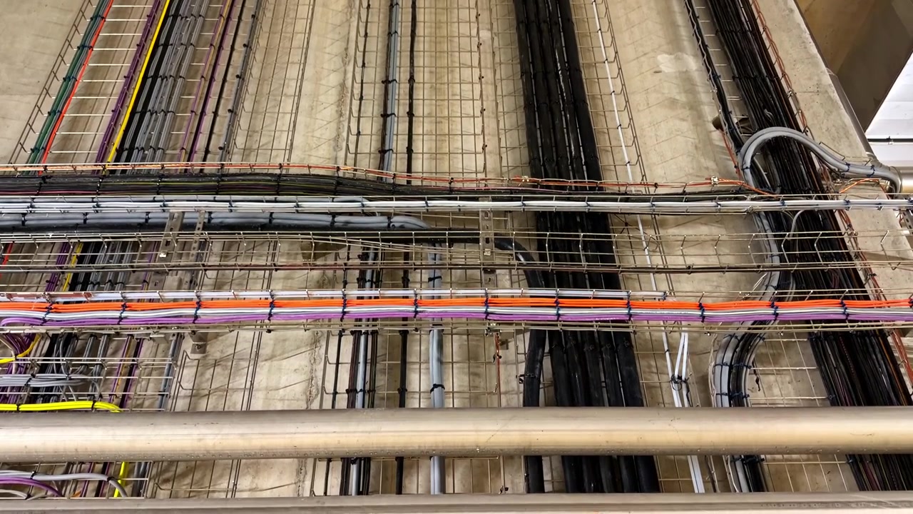 An intricate layout of cables and pipes runs along the ceiling of an industrial facility. Ideal for use in engineering or construction visuals.