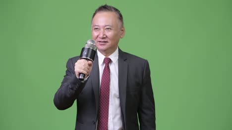 mature japanese businessman using microphone