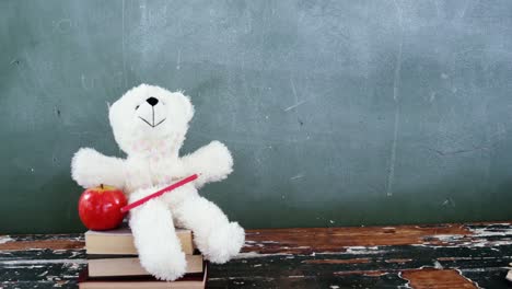 apple, teddy bear and pencil on book stack