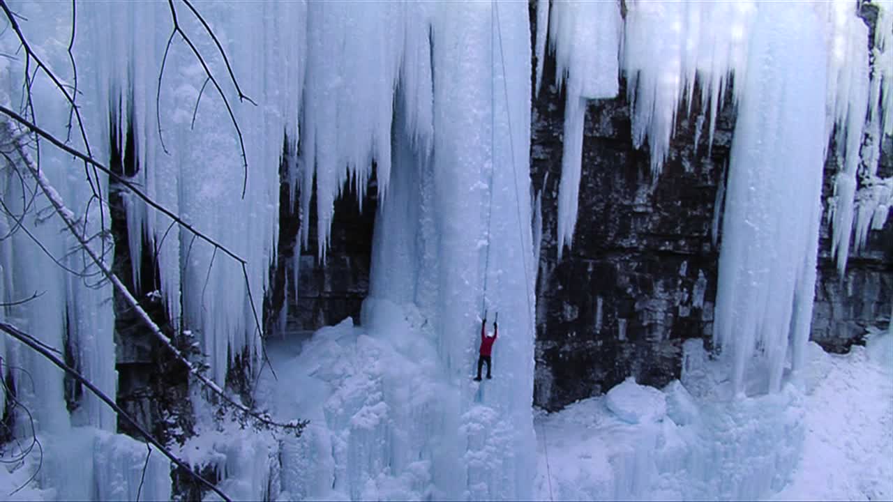 얼어붙은 폭포를 등반하는 남자의 와이드 샷