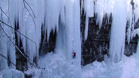 Weitwinkelaufnahme-Eines-Mannes,-Der-Auf-Einen-Gefrorenen-Wasserfall-Klettert