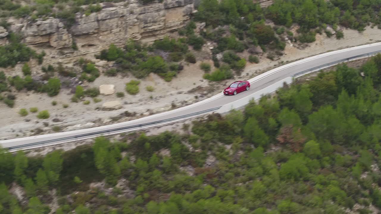 스페인 바르셀로나 인근 시골의 빈 구불구불한 도로를 가로질러 여행하는 빨간 자동차