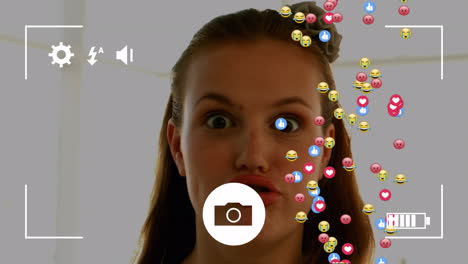 interfaz de la cámara sobre múltiples emoji de cara e iconos contra la mujer caucásica haciendo caras divertidas