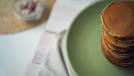 Stack-of-american-pancakes-on-green-plate-on-kitchen-table.-Pancake-breakfast