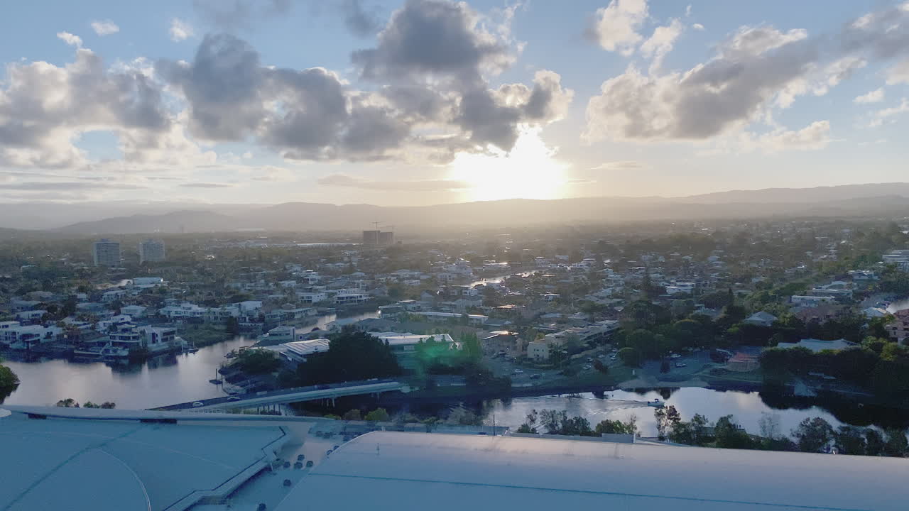 4K UHD Panning View of Casino construction, Convention Centre on the Nerang River at sunset in downtown Broadbeach district, Gold Coast Australia, aerial view. Commuter Tram, Gold Coast beach life.