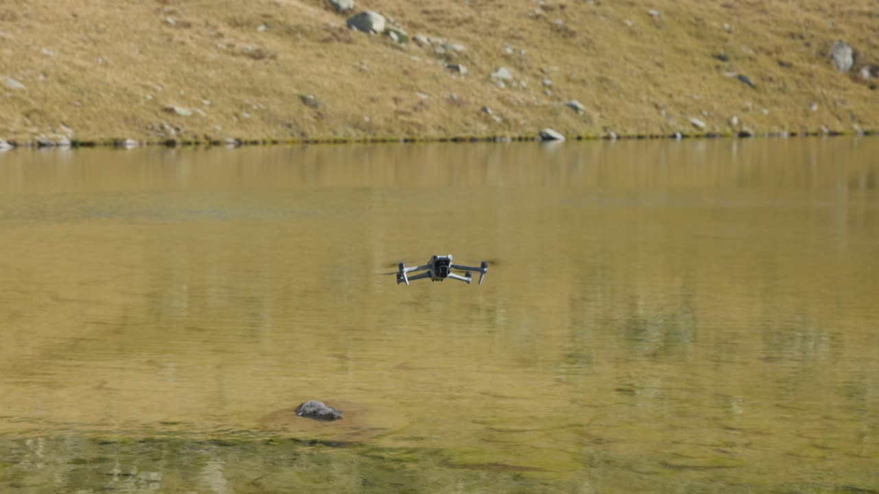 현대적인 드론이 작은 호수 위를 날고 있습니다.