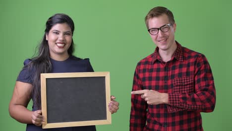 young multi-ethnic business couple together against green background