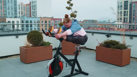 healthy caucasian sport woman exercising stretching workout on stationary cycle machine bike