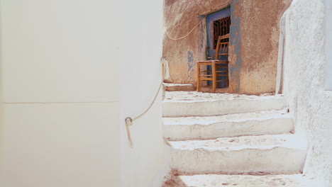 Chairs-sit-in-a-white-alley-on-the-island-of-Santorini-in-Greece