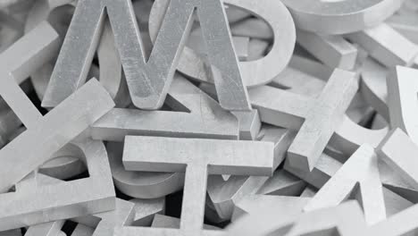 full frame close-up looped slowly rotating background of silver metal letters with selective focus