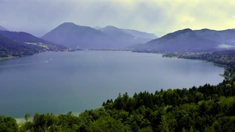 aerial view over the beautiful tegernsee at sunshine and light sunbeams, flying down the drone as crane shot