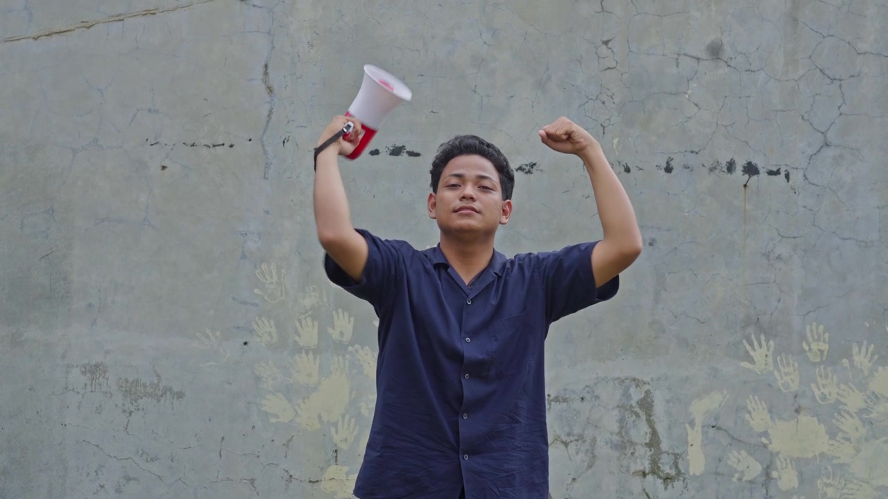 Aktivis pria muda berteriak ke megafon dan mengangkat kepalan tangan sebagai protes untuk konsep kebebasan pers