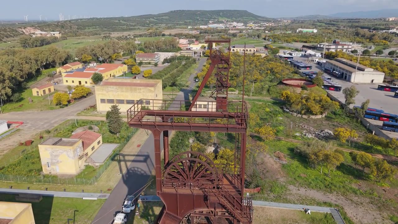 Cavalete da Mina de Carvão de Serbariu em Carbonia, Sardenha, Itália. Estrutura de aço da boca do poço do complexo histórico de mineração de carvão. Tomada aérea com inclinação para cima.