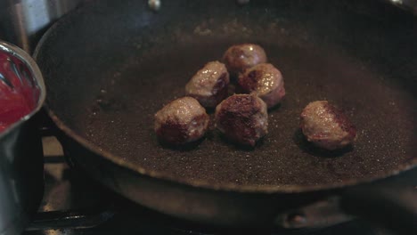 slow motion push in shot revealing browned and cooked meatballs in a pan