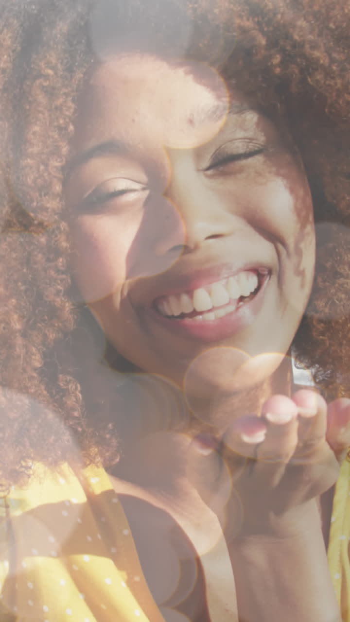 animación de bokeh sobre una feliz mujer biracial enviando besos