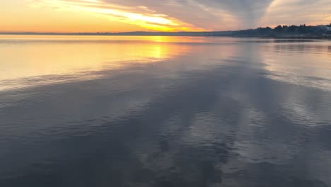 Goldener-Orangefarbener-Sonnenuntergang-über-Einem-Ruhigen,-Reflektierenden-See