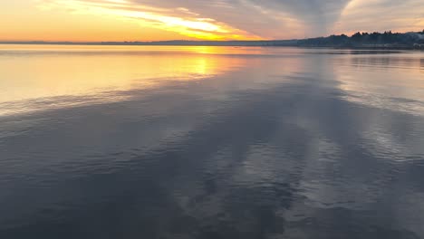puesta de sol de color naranja dorado sobre un lago tranquilo y reflectante