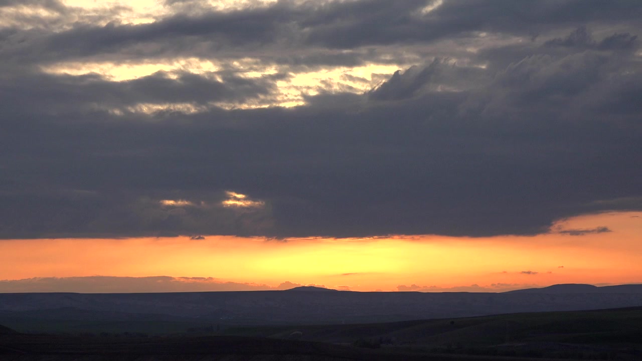 Dramatic Sunset Over Rolling Hills With Dark Storm Clouds