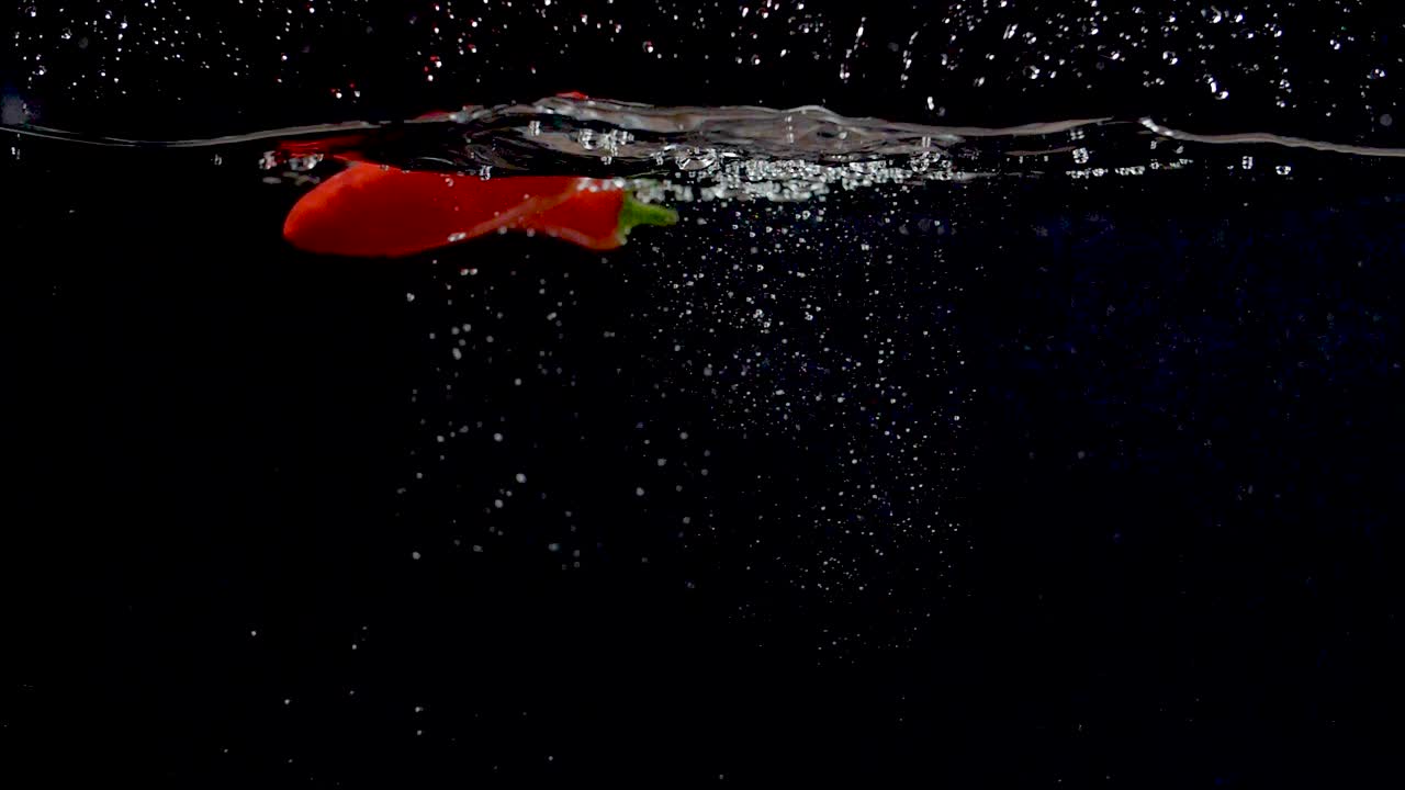 느린 동작으로 물에 떨어지는 화려한 붉은 달콤한 고추