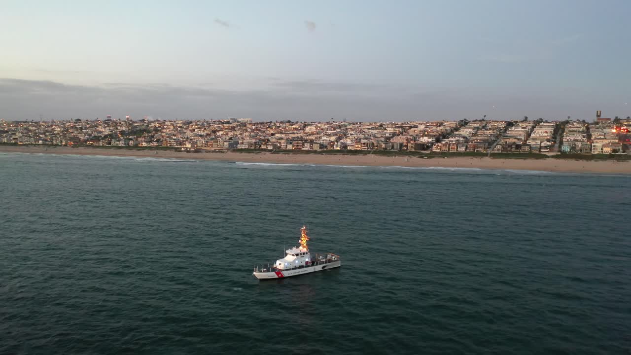 el barco de guardacostas navega cerca del centro de la playa de manhattan en california, ee.uu.