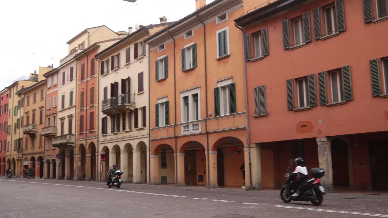 Motorbikes passing through a picturesque street in Bologna, Italy