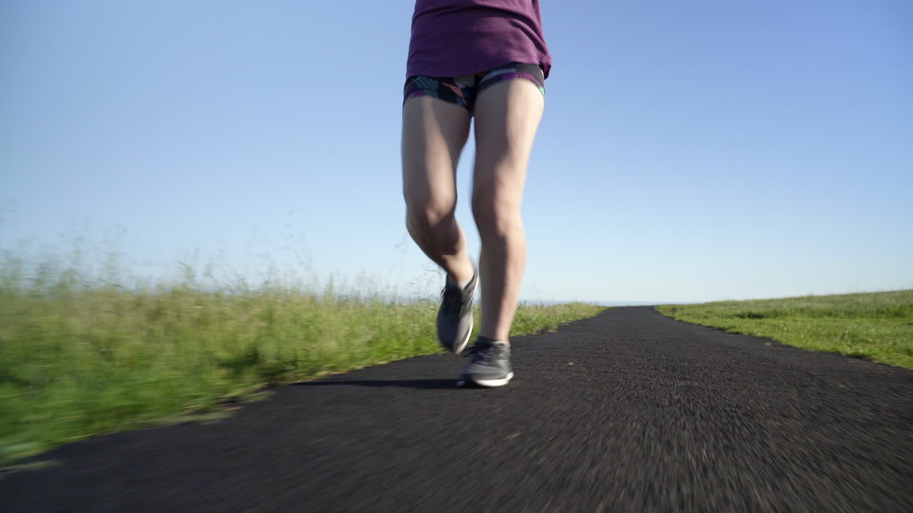 Legs of Young Woman Running on a Track at Sunset