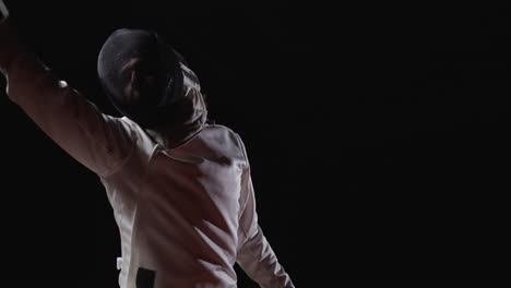 man in fencing gear posing with foil sword