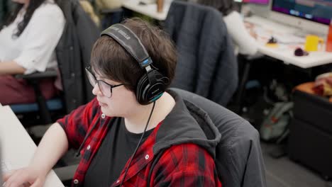 focused woman in headphones working at a computer in an open office