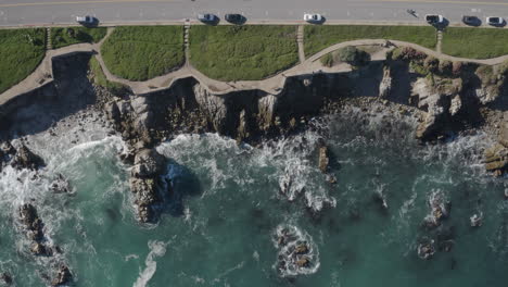 4k overhead of a beautiful day on the monterey bay recreation trail in pacific grove california with the waves gently breaking on the shore and ocean view boulevard at the top of frame