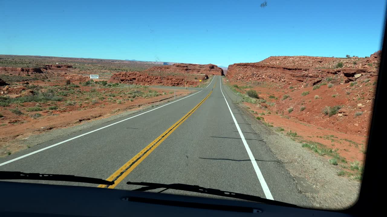 Vista de conducción por una carretera desértica sinuosa a través de un paisaje de rocas rojas