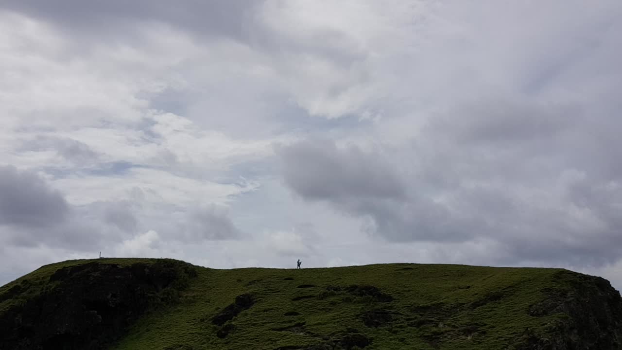 필리핀 바타네스의 두꺼운 구름 아래 언덕을 가로질러 걷는 남자의 실루엣